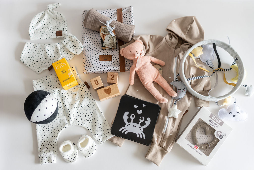 Collection of baby items including clothes, toys, and accessories on a light background